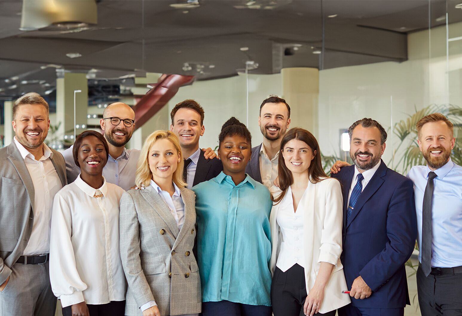 A diverse group of professionals stands together posing for a photo in an office.